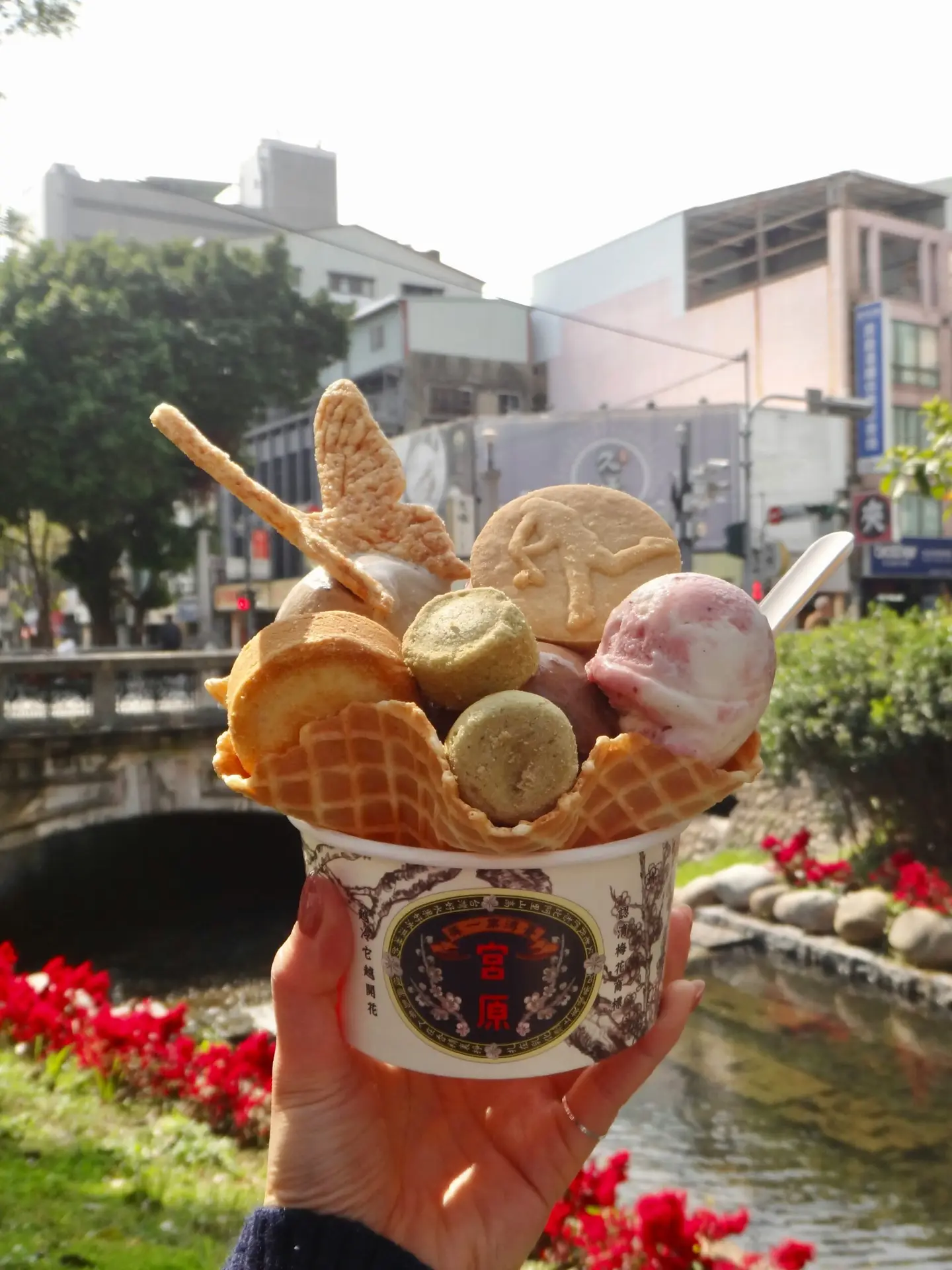 Hand holds a large ice cream sundae outside.